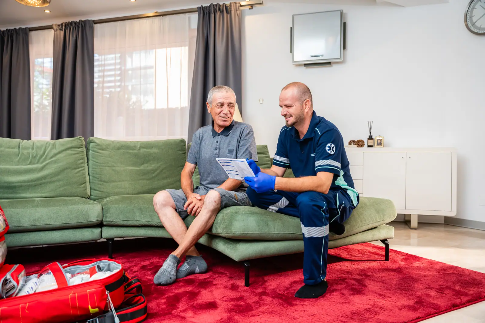 Asistent medical TRUMED lângă un pacient vârstnic, în camera de zi