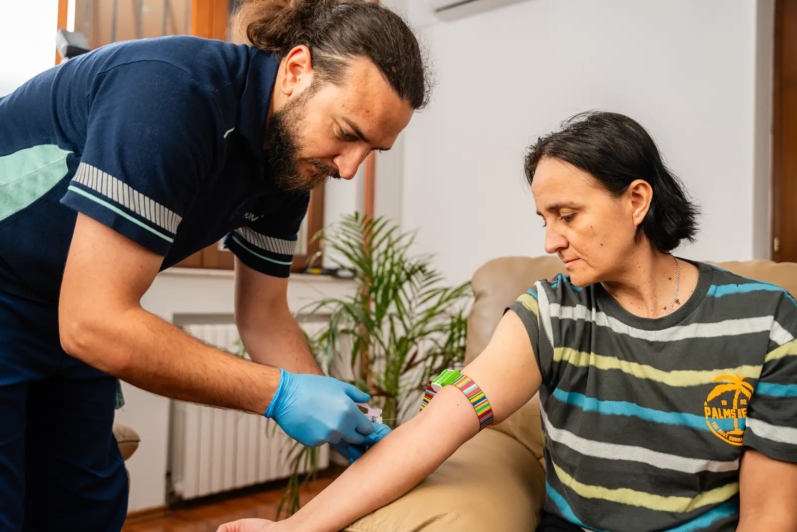 Asistent medical TRUMED recoltează sânge de la o pacientă, acasă